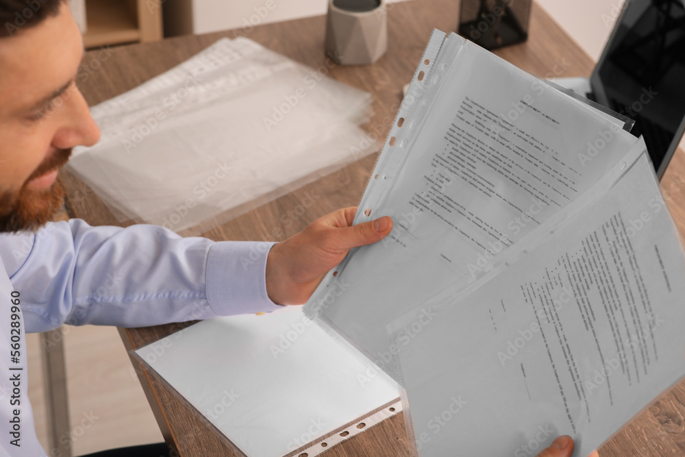 Naklejka premium Businessman working with documents at wooden table in office, closeup