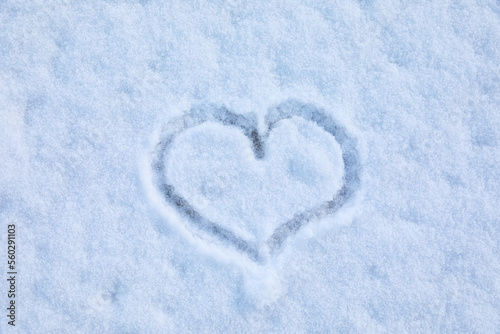 Heart drawn on snow, top view. Winter season