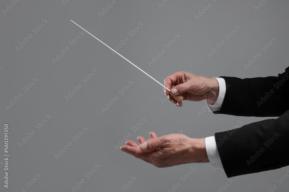 Professional conductor with baton on grey background, closeup - obrazy, fototapety, plakaty 