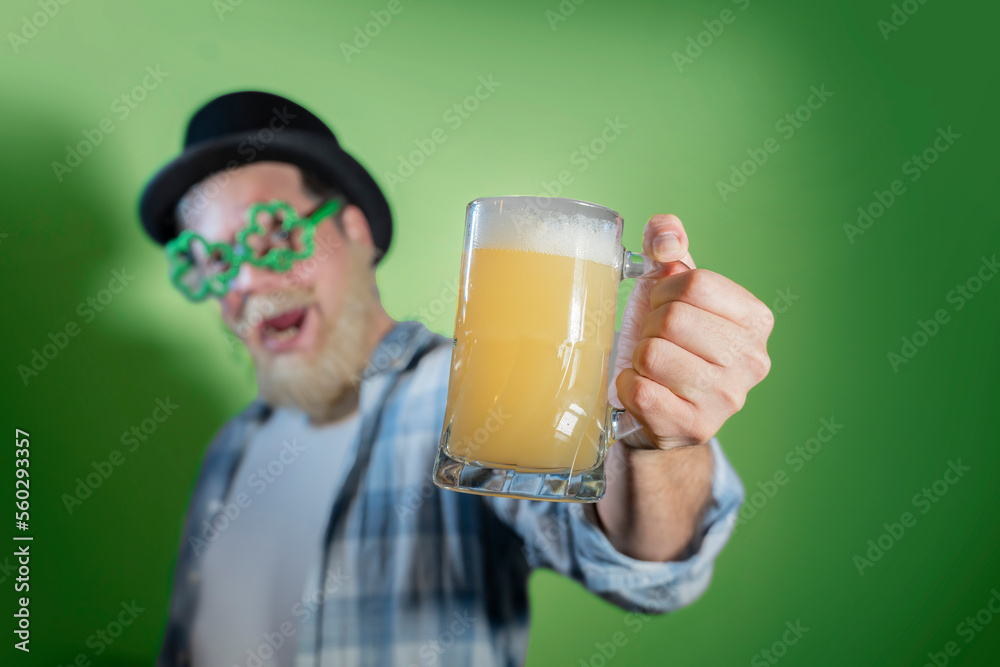 Funny bearded man celebrates St. Patrick's Day and holds mugs of beer