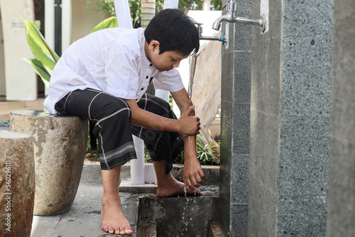 Muslim kid washing hands from hands to elbow, procedure of ablution before pray salah at the mosque