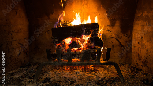 Fire in fireplace. Burning logs in warm stone fireplace background. Cozy winter evening by the fire concept