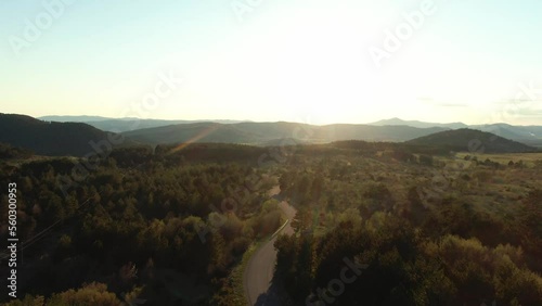 A drone shot with the road in the middle. The sun is setting so the light and the atmosphere are warm and cozy. There are almost no clouds in the sky. photo