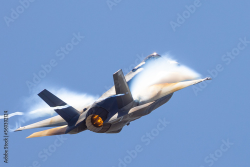 Very unusual close view of a F-35A Lightning II in a high G maneuver , with condensation clouds around the plane and afterburner on photo