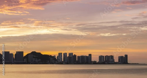 timelapse silhouette view of waterfront city with highrise skyscraper building near sea coast beach while sunset sundown time with vanilla twilight sky