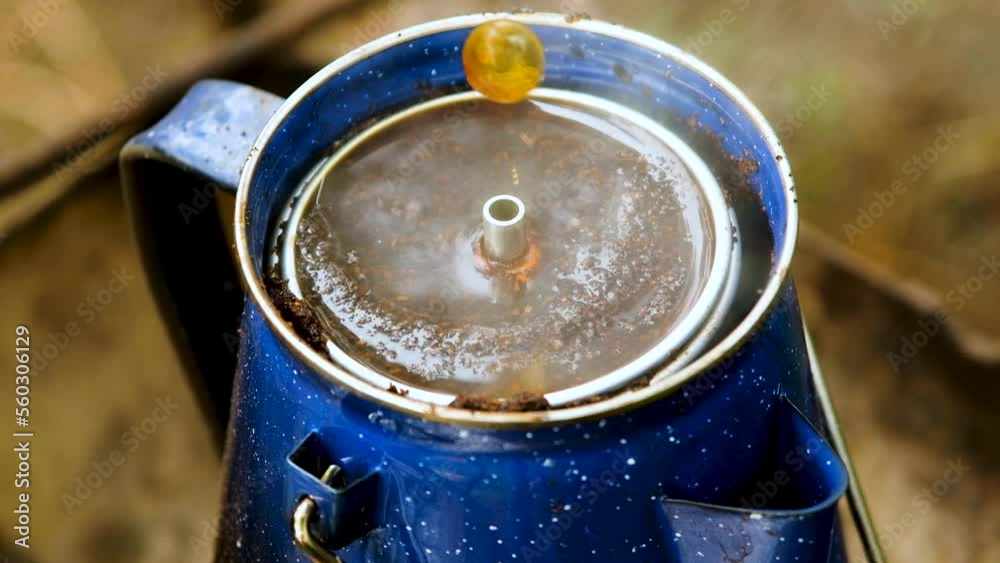 Close up of enamel percolator coffee set on fire spewing out hot black coffee Close up of enamel percolator coffee set on fire spewing out hot black coffee