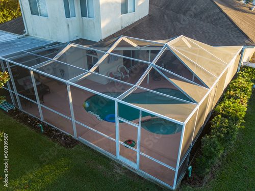 Pool screen enclosure with aluminum beams protecting patio in neighborhood home in Florida