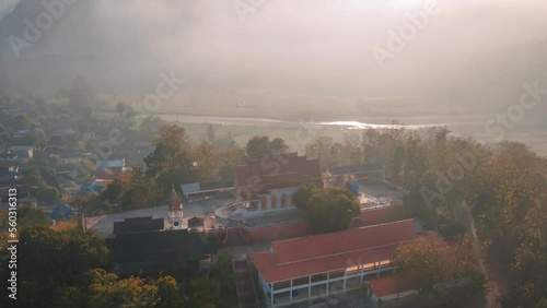 Motion time lapse during morning fog with the red church of Buddhism temple on top of the mountain in Mae Sariang district of Mae Hong Son province Thailand. Aerial point of interest view photo
