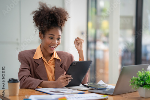 African American businesswomen celebrate winning or getting e-commerce shopping offers on a digital tablet. Excited happy girl winner looking at a digital tablet celebrating success.