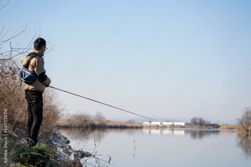 真冬の川でバス釣りをする男性