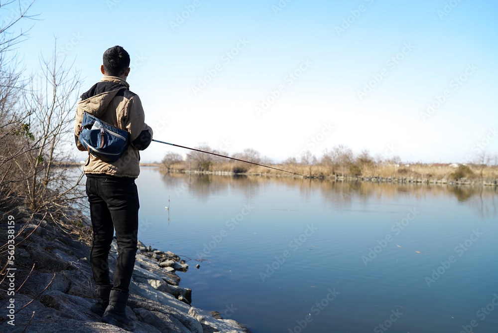 Obraz premium 真冬の川でバス釣りをする男性