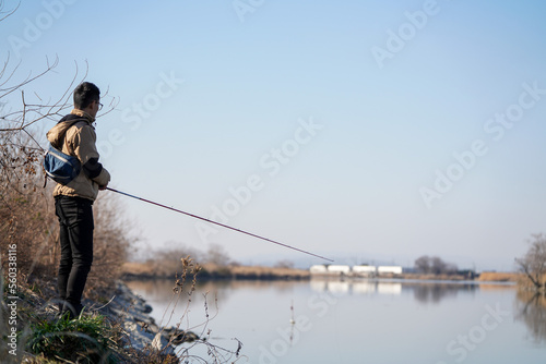 真冬の川でバス釣りをする男性