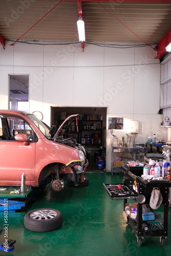 整備工場で車検整備をしているオレンジ色のクルマ
