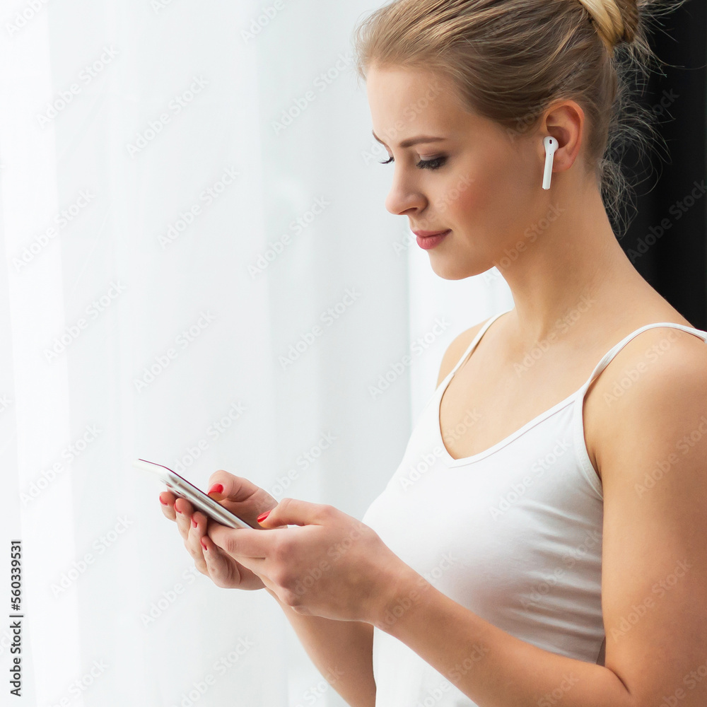 Young woman in white underwear is standing in front of the window and looking into it. Girl at home in the living room. Young woman in white underwear is standing in front of the window and looking into it. Girl at home in the living room.