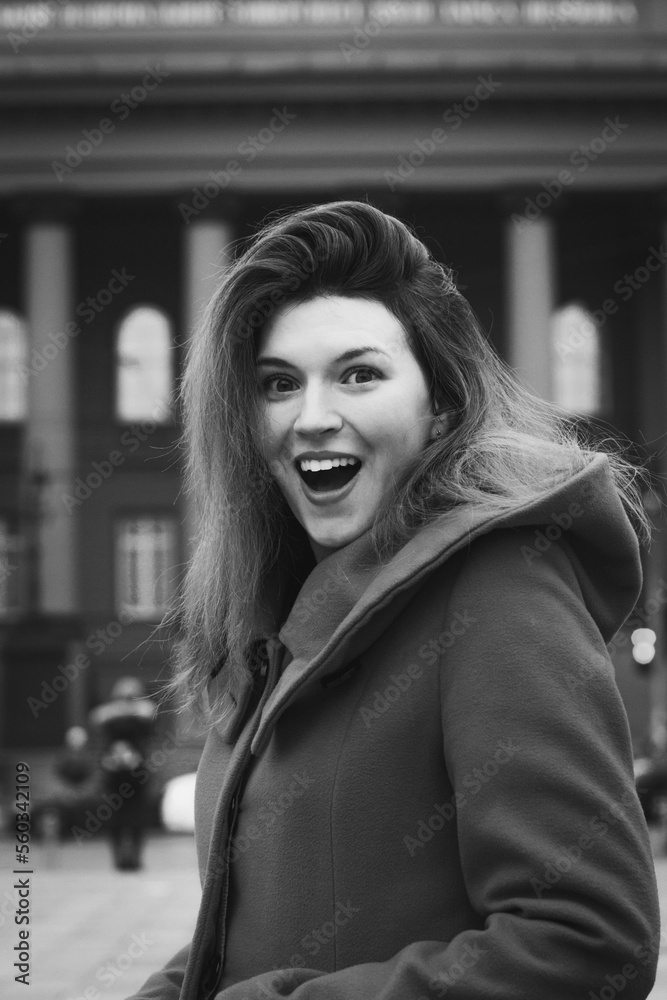 Close up happy emotional woman on street monochrome portrait picture. Closeup side view photography with city building on background. High quality photo for ads, travel blog, magazine, article Close up happy emotional woman on street monochrome portrait picture. Closeup side view photography with city building on background. High quality photo for ads, travel blog, magazine, article