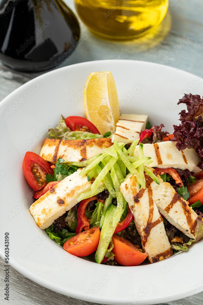 Salad with tomato and halloumi cheese on wooden table Salad with tomato and halloumi cheese on wooden table
