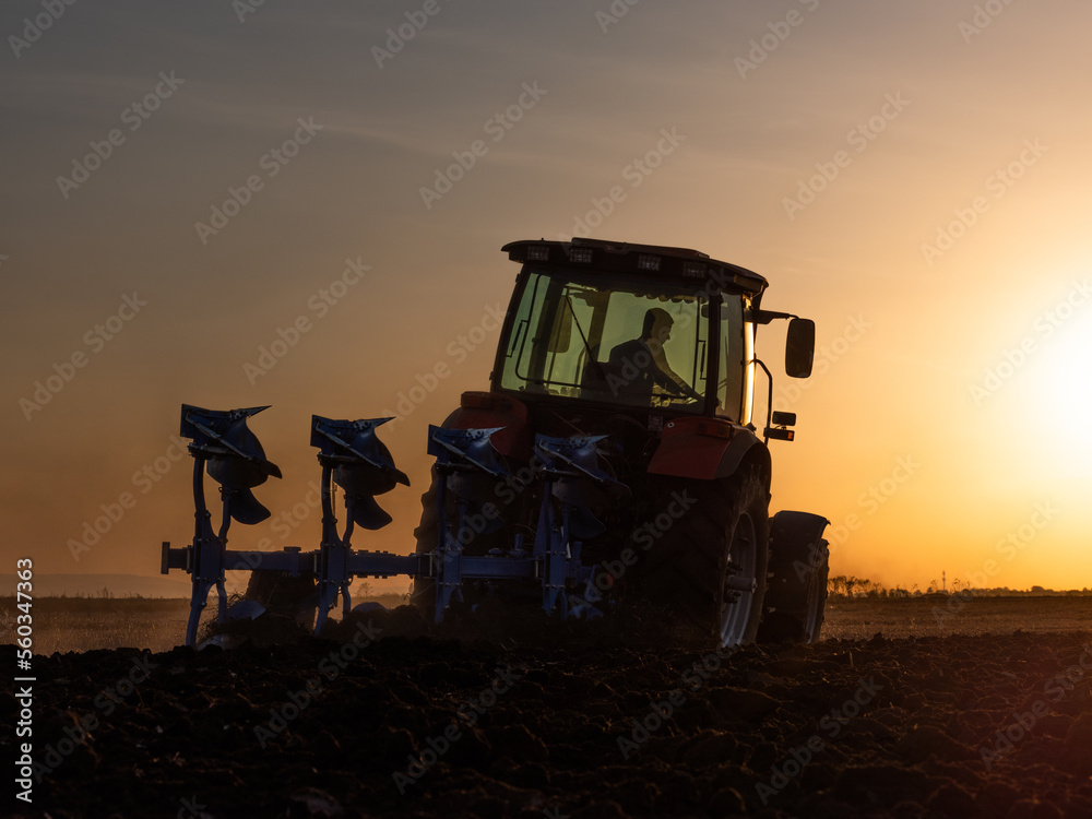 Fototapeta premium Farmer in tractor cultivating stubble field in preparation for seeding