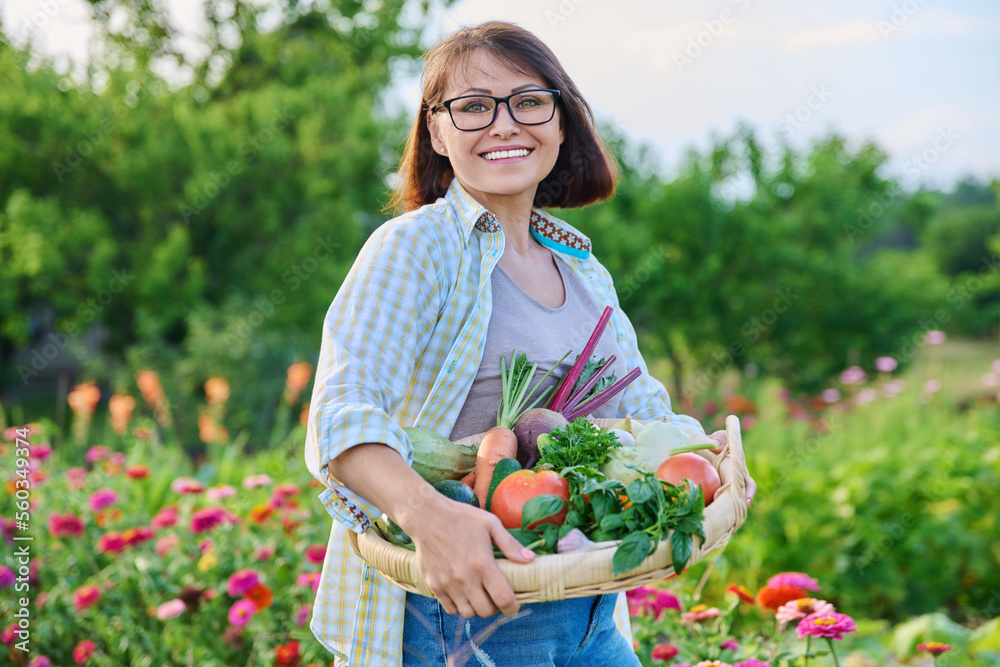 Portrait of smiling woman with basket of different fresh vegetables and herbs Portrait of smiling woman with basket of different fresh vegetables and herbs