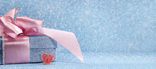 Red heart. Blue sparkling gift box with pink ribbon bow on blue bokeh background. Gift or holiday concept. Mothers Fathers Day, birthday wedding or St Valentines day with copy space.