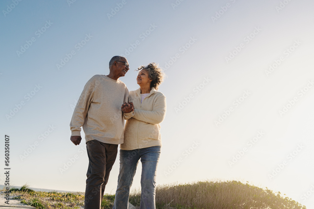 Low angle view of a senior couple walking down a foot bridge at the beach Low angle view of a senior couple walking down a foot bridge at the beach