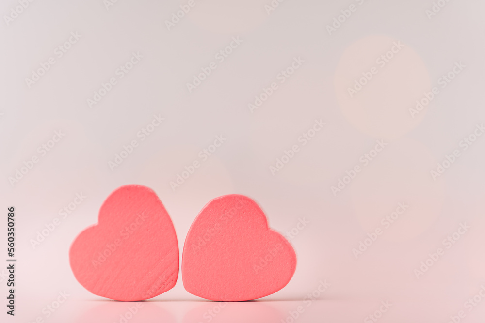 Two red hearts against blurred pink background.