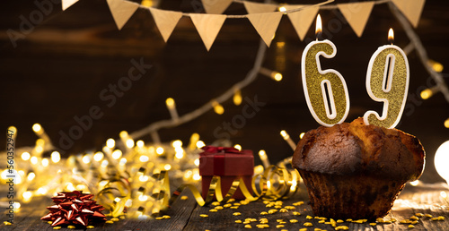 Number 69 golden festive burning candles in a cake, wooden holiday background. sixty nine years since the birth. the concept of celebrating a birthday, anniversary, holiday. Banner. photo