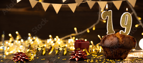 Number 79 golden festive burning candles in cake, wooden holiday background. seventy nine years since the birth. the concept of celebrating a birthday, anniversary, holiday. Banner. photo