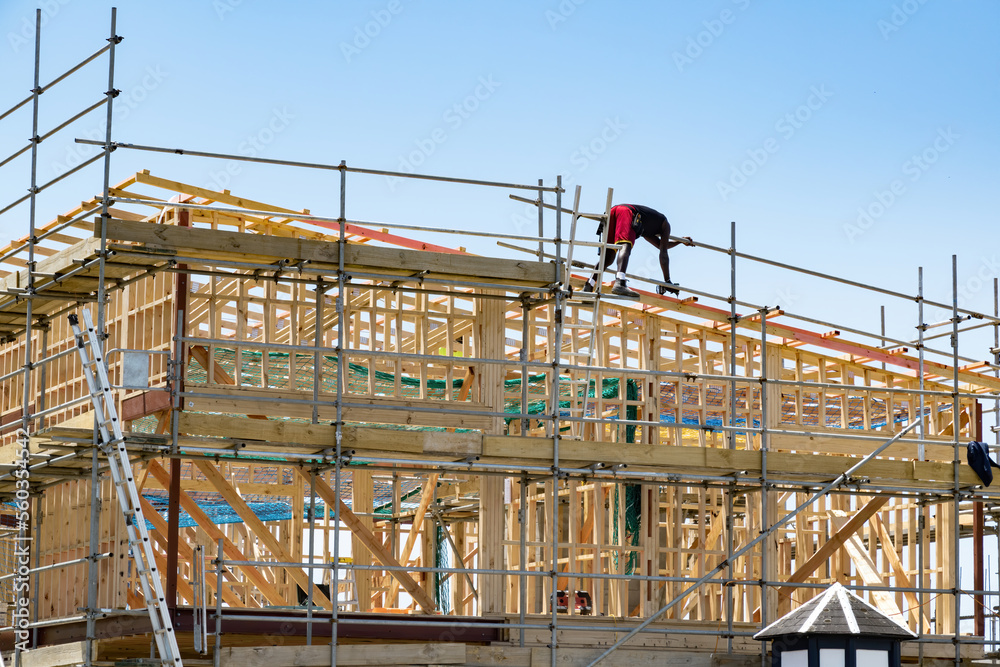 Construction site with wooden frame and worker on roof