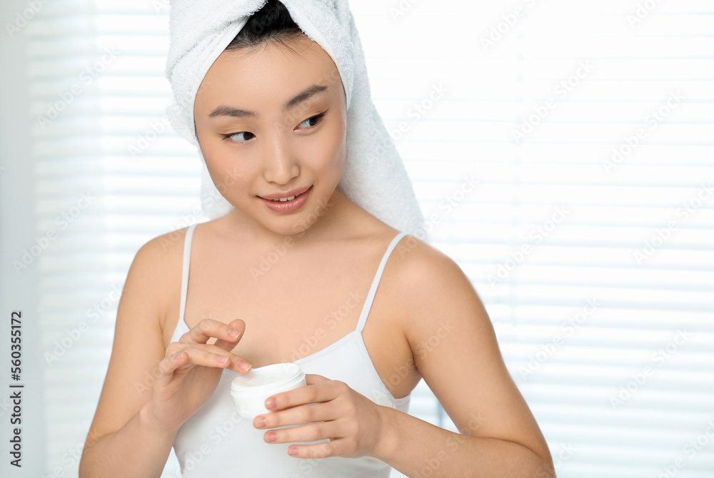 Beautiful young Asian woman holding body cream in room Beautiful young Asian woman holding body cream in room
