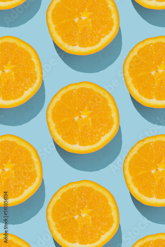 Pattern made of fresh orange halves on blue background. Minimal fruit concept.