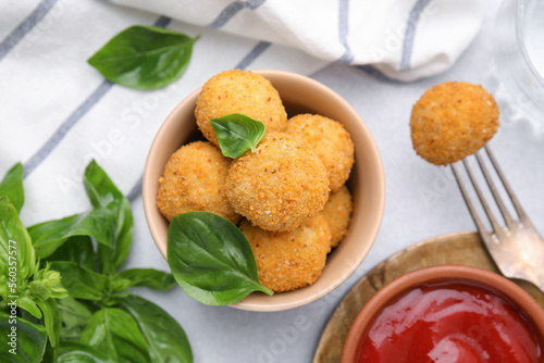 Bowl of delicious fried tofu balls with basil and ketchup on white table, flat lay