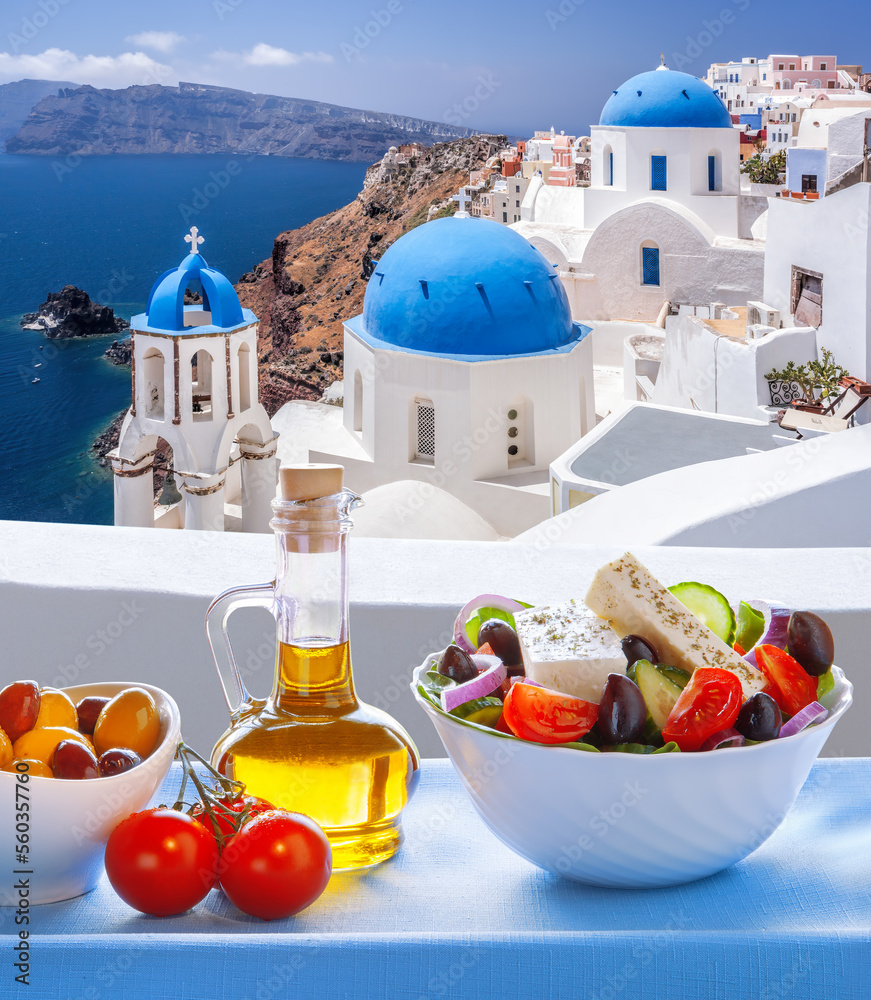 Greek food against famous churches in Oia village on Santorini island in Greece