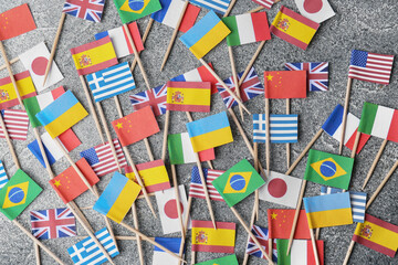 Many small paper flags of different countries on grey table, flat lay