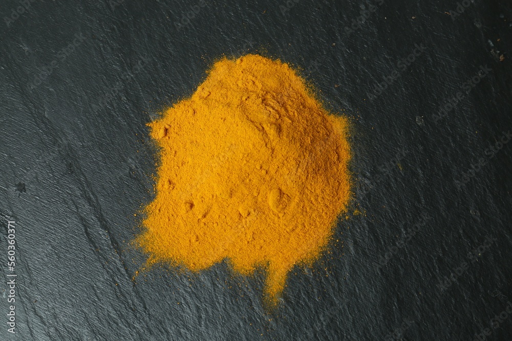 Turmeric powder on black textured table, top view Turmeric powder on black textured table, top view