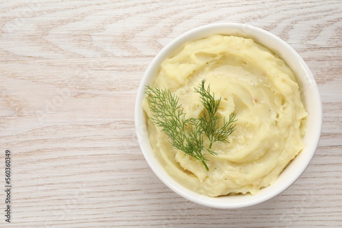 Bowl of tasty mashed potato with dill on wooden table, top view. Space for text