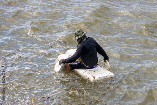 A man floating on a polystyrene and used a lids for paddled