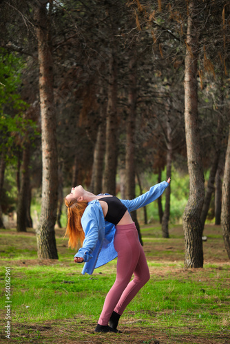 Redhead young woman practicing contemporary dance in a forest. Dancer in nature.