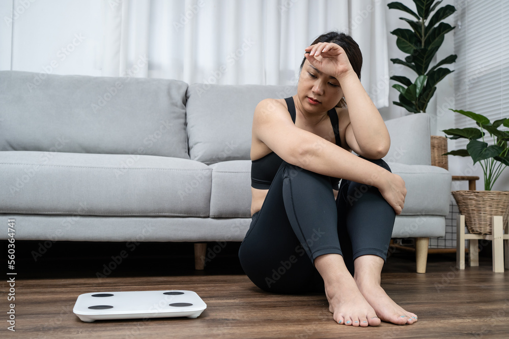 Asian healthy woman bored of dieting Weight loss fail Fat diet and scale sad asian woman Upset on weight scale at home weight control. Asian healthy woman bored of dieting Weight loss fail Fat diet and scale sad asian woman Upset on weight scale at home weight control.