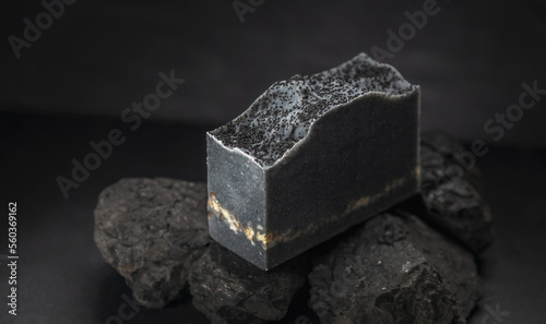 Piece of natural charcoal soap on real coals on a black background. Concept of making and using organic eco soap and cosmetics