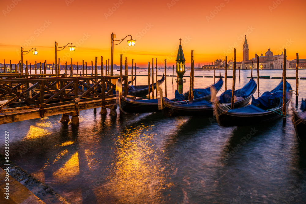 Long exposure: Gondolas floating by the shoreline of San Marco Square at sunrise in front of the Island of San Giorgio Maggiore in Venice, Italy