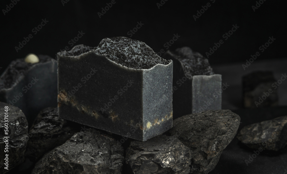 Natural charcoal soap on real coals on a black background. Concept of making and using organic eco soap and cosmetics Natural charcoal soap on real coals on a black background. Concept of making and using organic eco soap and cosmetics