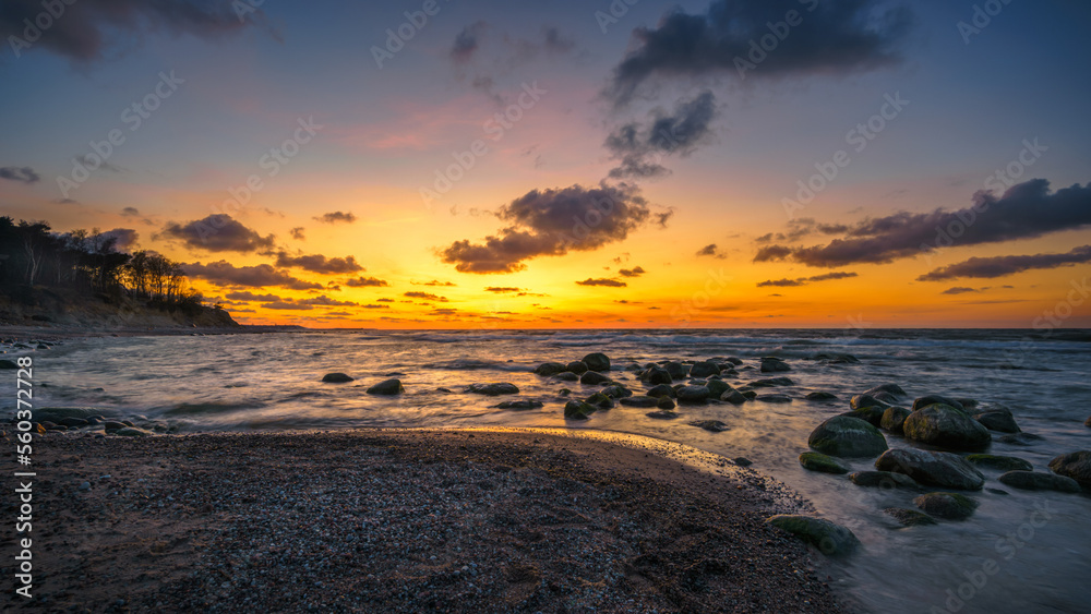 Wonderful orange sunset on the rocky coast of the sea