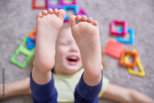 Close-up of the legs of a child laughing on the carpet