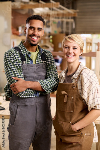 Portrait Of Male And Female Apprentices Working As Carpenters In Furniture Workshop