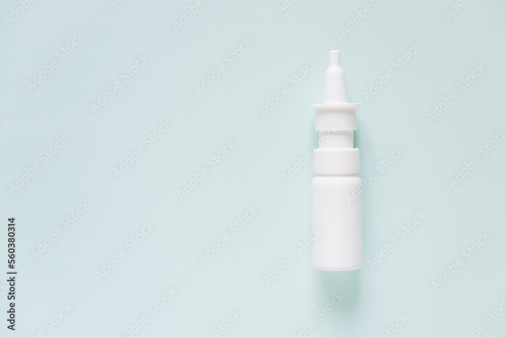 White plastic bottle of medical nasal spray on a blue background. Pharmaceutical packaging layout. Allergy runny nose remedy, rhinitis therapy. White plastic bottle of medical nasal spray on a blue background. Pharmaceutical packaging layout. Allergy runny nose remedy, rhinitis therapy.