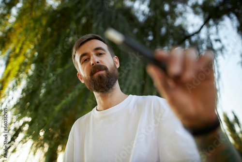 A man smokes an electronic cigarette in the park. 