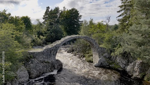 Ruin of medieval ancient Stone Packhorse Bridge over Dulnain river, Carrbridge, Scotland, UK with strong water flow photo