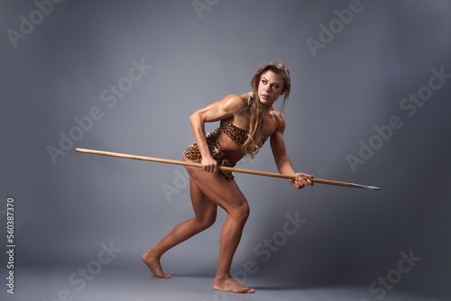 Muscular female prehistoric hunter crawling with spear