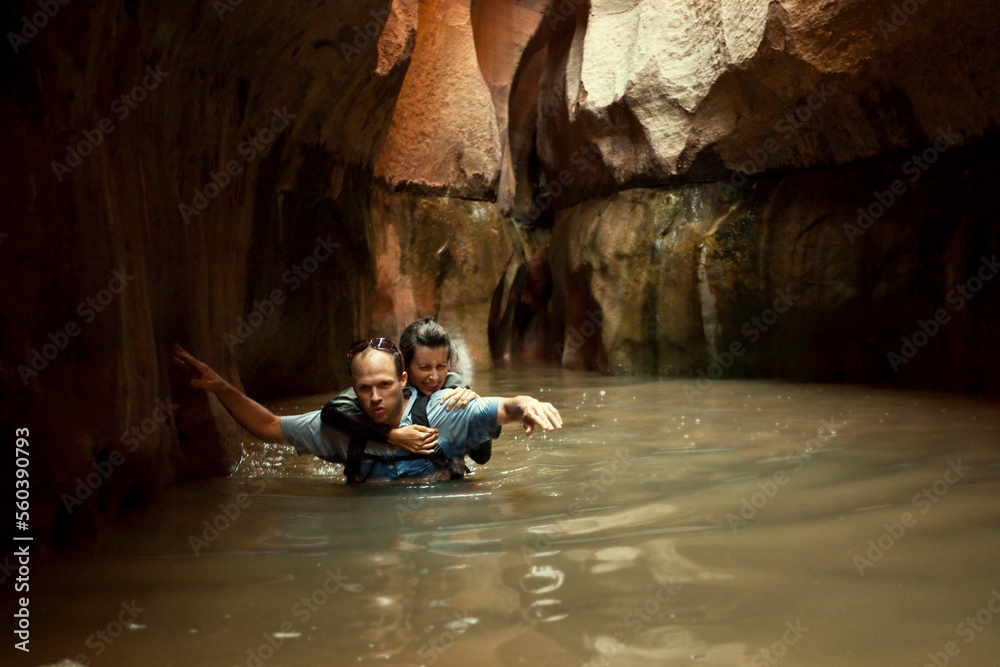 A couple wades through a cold pool in a slot canyon in Utah. A couple wades through a cold pool in a slot canyon in Utah.