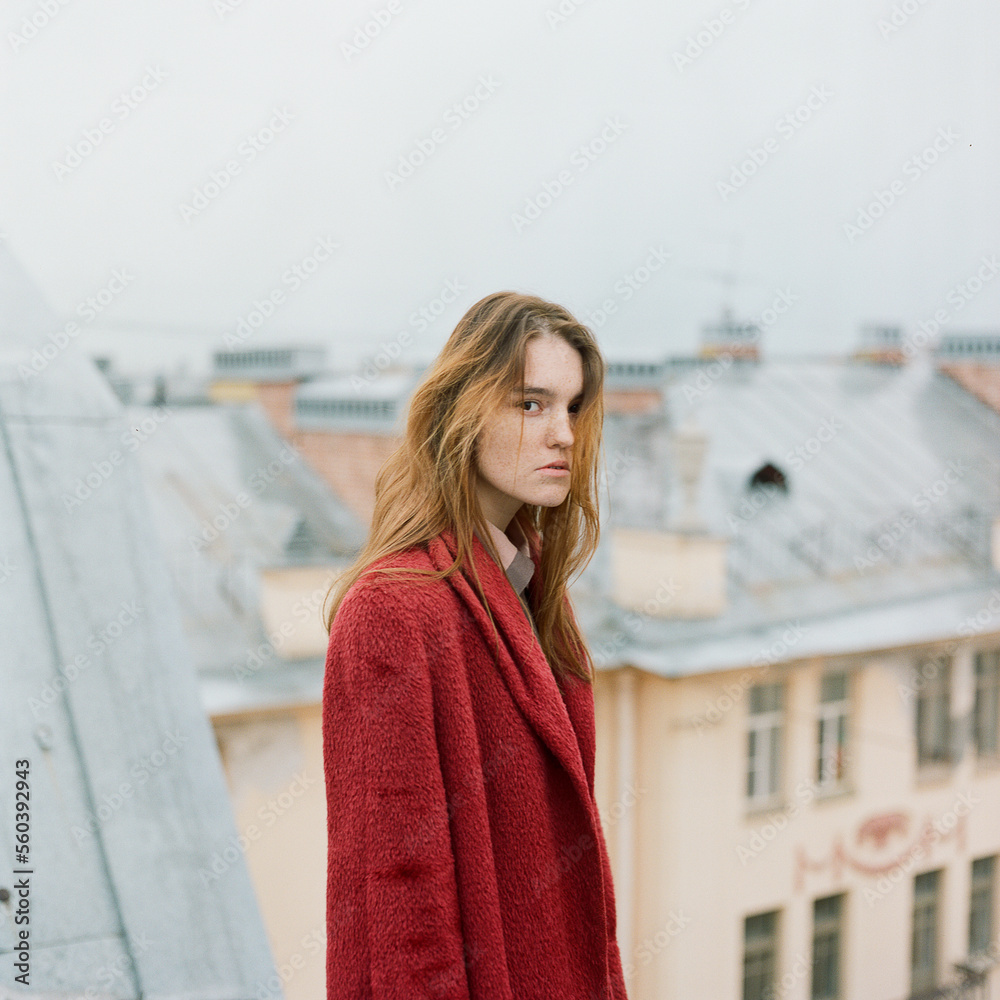 Portrait of beautiful brunette woman in red coat standing on the roof Portrait of beautiful brunette woman in red coat standing on the roof